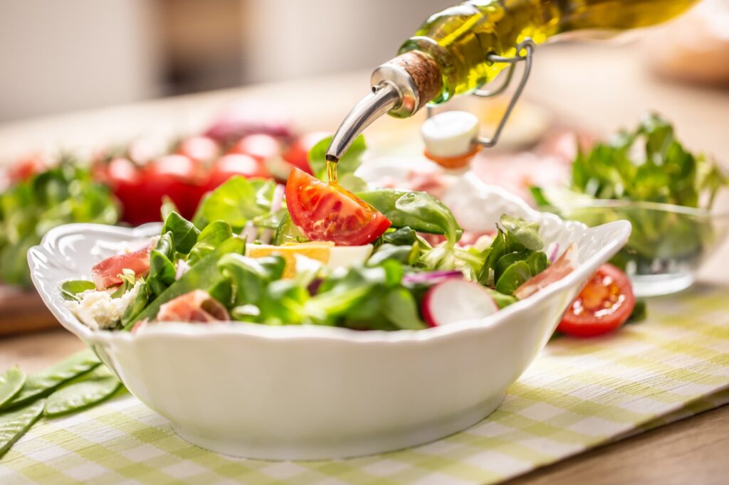 Bouteille d’huile d’olive versée sur une salade.
